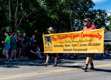 Peninsula Country Market sign carried by volunteers in parade